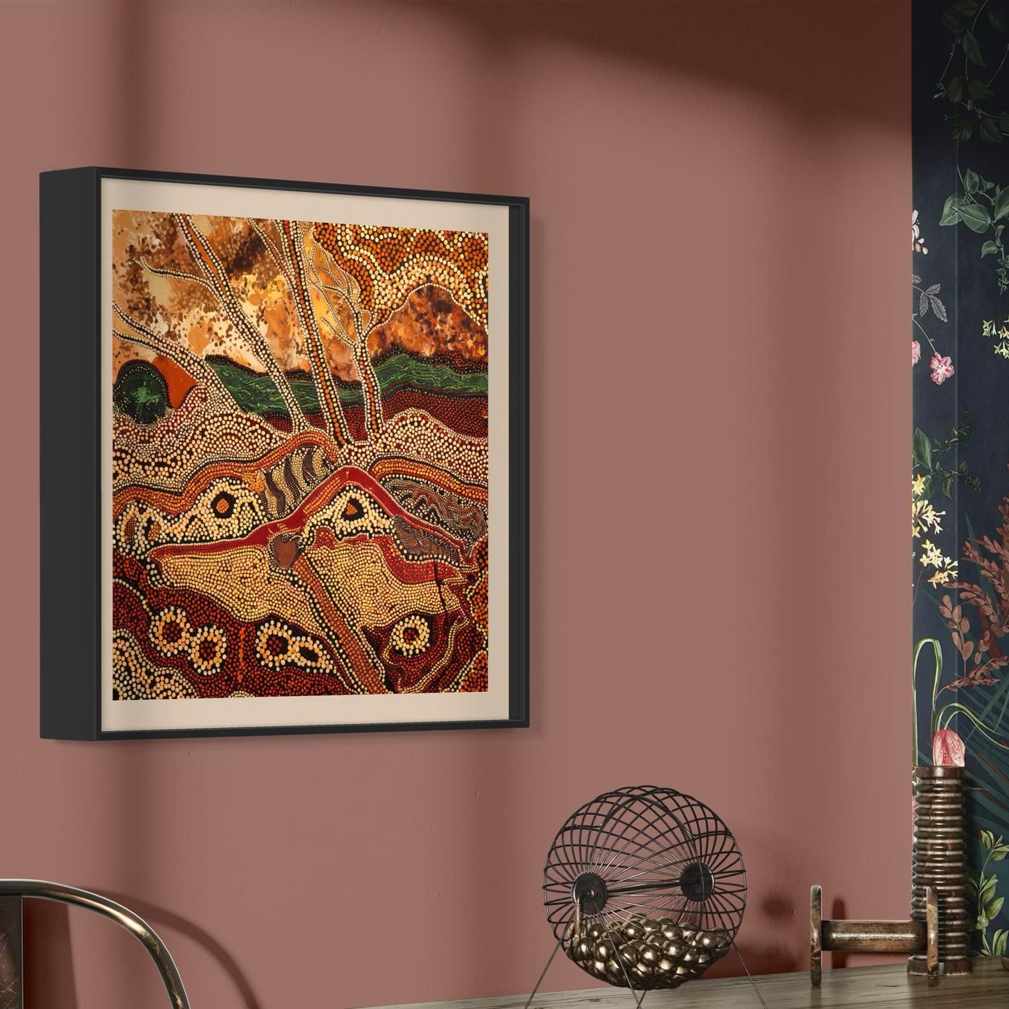 Dreaming Landscape Aboriginal dot painting printable in earthy tones framed on terracotta wall beside floral wallpaper and modern decor