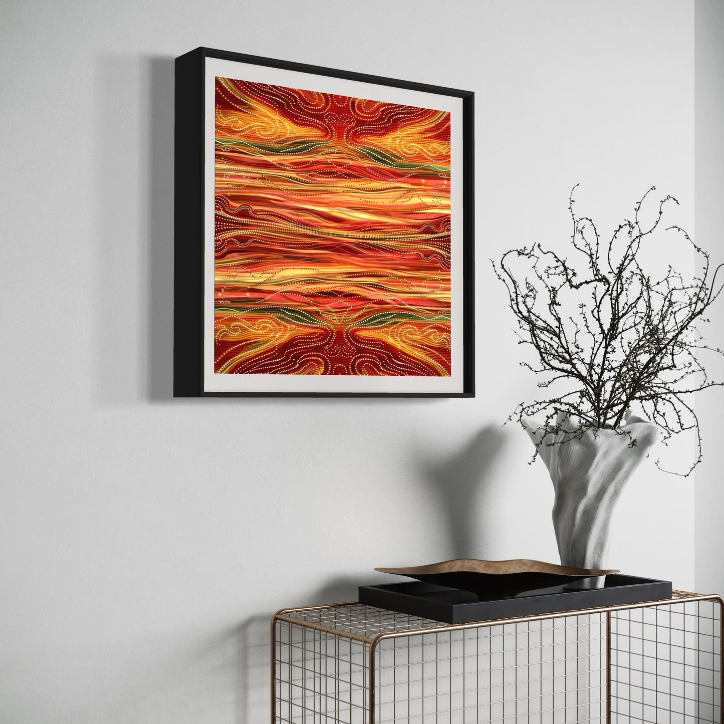 Yurala Flames Aboriginal dot painting printable in fiery earth tones, framed and displayed on a white wall above a modern wire console with sculptural decor and a twisted branch vase.