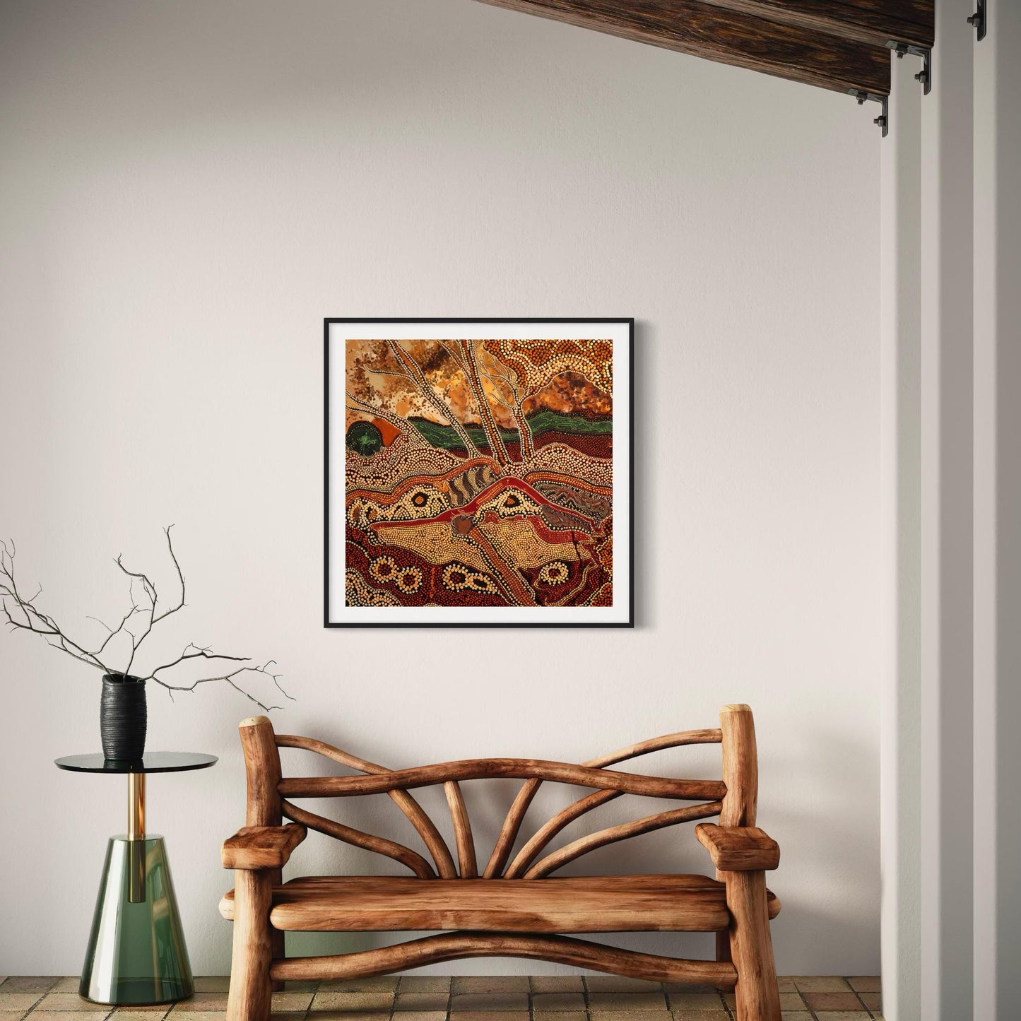 Dreaming Landscape Aboriginal dot painting printable in earthy tones framed on light wall above curved wooden bench and black vase with branches