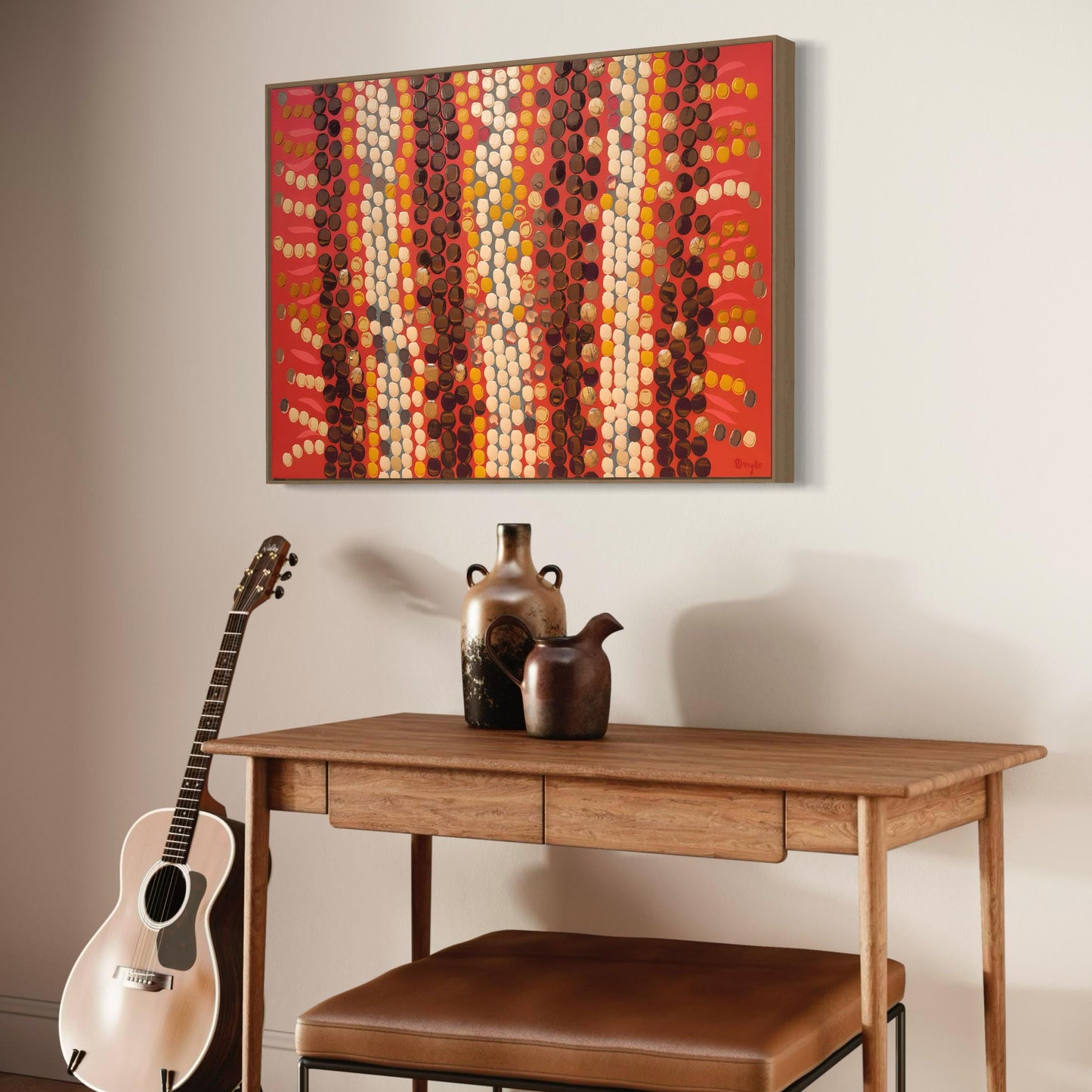 Horizontal Aboriginal dot painting in earthy reds, browns, and creams, displayed above a wooden desk with pottery vases, a brown leather bench, and a guitar leaning against the wall.