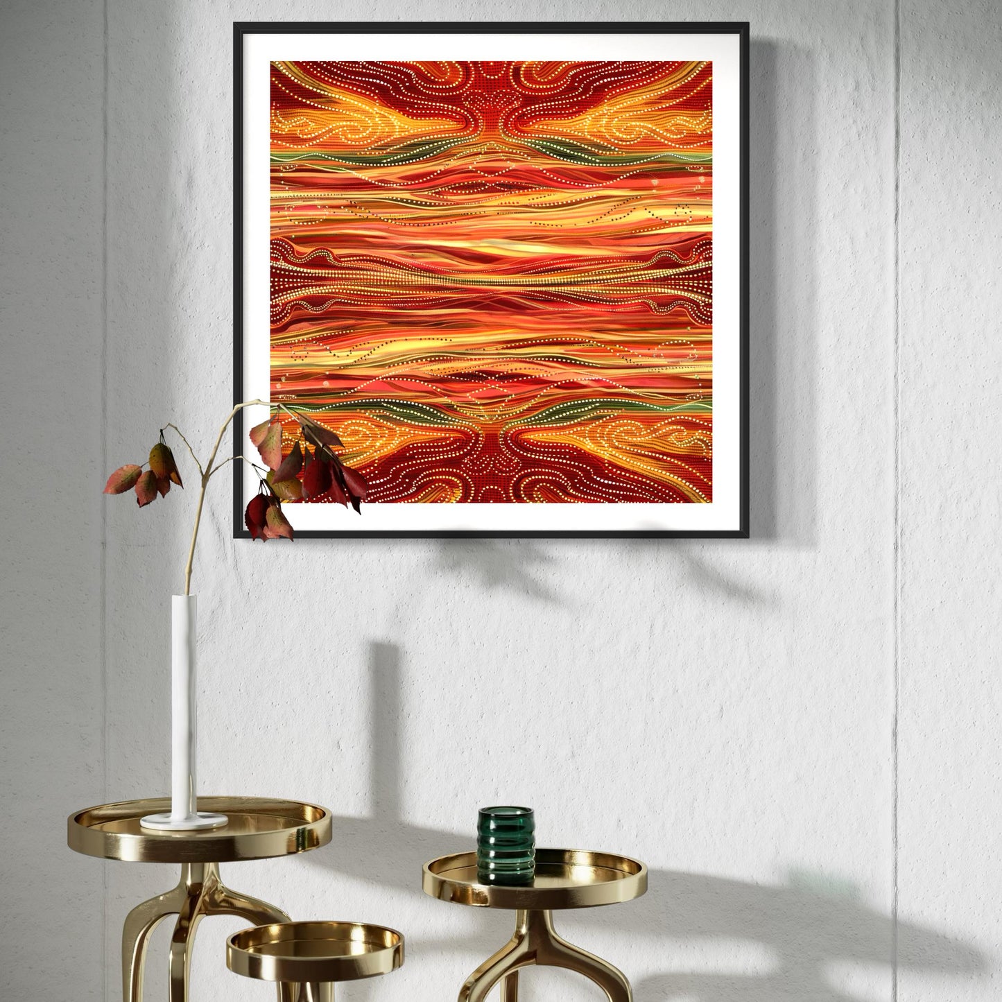Yurala Flames Aboriginal dot painting printable in warm reds, oranges, and golds, framed and displayed on a white textured wall above brass nesting tables with minimalist decor and a single-stem vase.